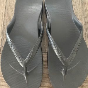 Archie’s black flip flops